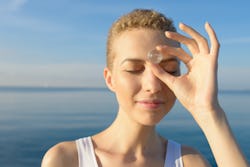 A woman holds a quartz up to her third eye. These are the zodiac signs most likely to be psychic.