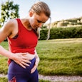 Sporty woman outdoors, holding her stomach in pain
