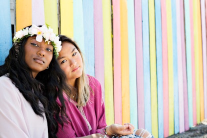 Friends sitting in front of a pastel wall would need April captions and quotes for Instagram.