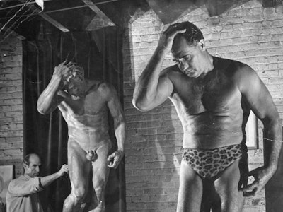 Charles Atlas posing while a sculptor works.    (Photo by George Karger/Getty Images)