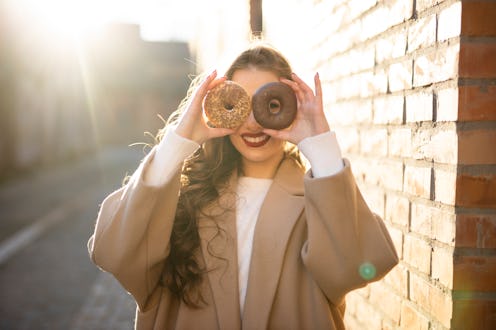 Happy young girl having fun with donuts