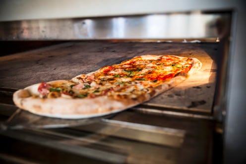 A pizza being removed from an oven