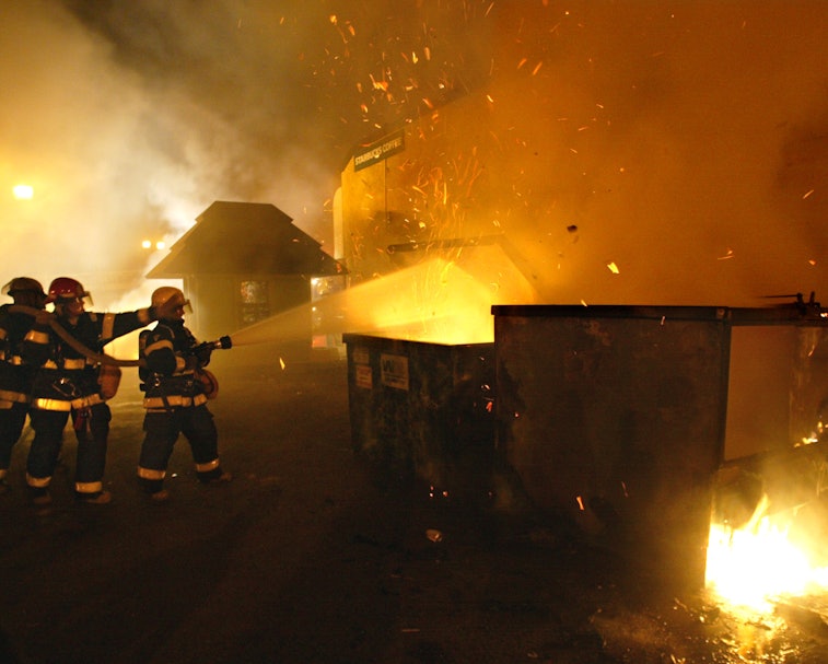 04/12/03 - Dinkytown - Minneapolis firemen put out a fire in a garbage dumpster in a parking lot nex...