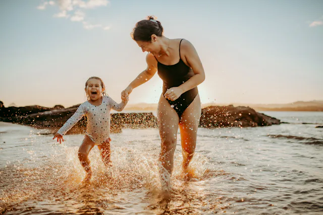 Mother and daughter having fun on the beach at sunset.