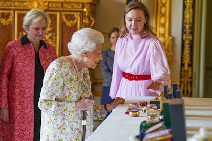 Britain's Queen Elizabeth II (C) views a display of artefacts from Halcyon Days to commemorate the c...