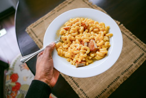 Close-up of unrecognizable black woman carrying bowl of macaroni and cheese with chicken