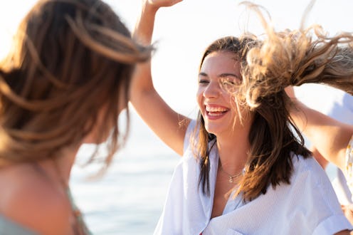 Young woman smiling and dancing on sailing boat in sea.