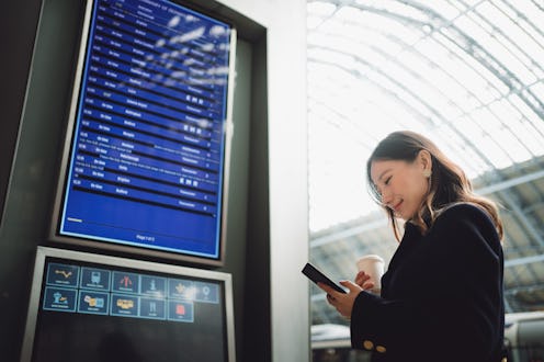 Asian beautiful traveler looking at departure information at a train station.