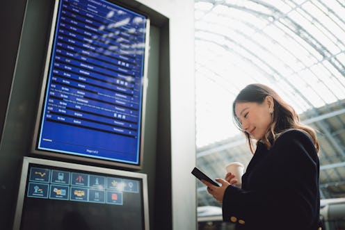 Asian beautiful traveler looking at departure information at a train station.