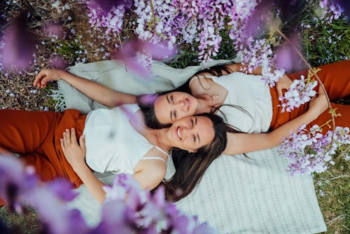 Two twins lie on a picnic blanket surrounded by flowers. These are gemini zodiac sign's hidden power...