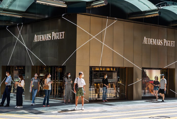 HONG KONG, CHINA - 2021/10/06: Pedestrians wait at a traffic light in front of the Swiss manufacture...