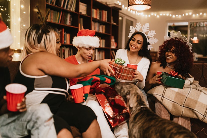 A group of young adult friends gather at a home for Christmas celebration over the holiday, dressed ...
