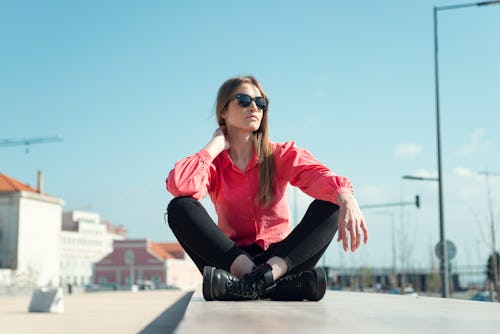 A woman sits on a wall looking out to the sea. Here's your daily horoscope for March 4, 2022.