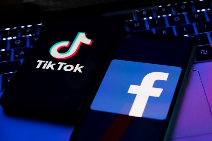 TikTok and Facebook logos displayed on phone screens and a laptop keyboard are seen in this illustra...
