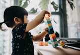 Creative little toddler girl playing with colourful building blocks at home
