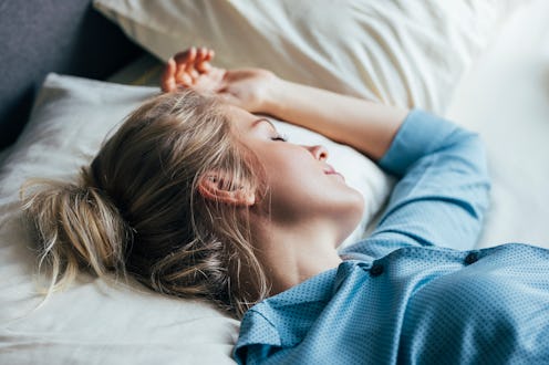 A side view of a young female sleeping in her blue pajamas.