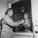 American actress Lucille Ball (1911 - 1989) passing a coffee tray to her husband, actor and musician...