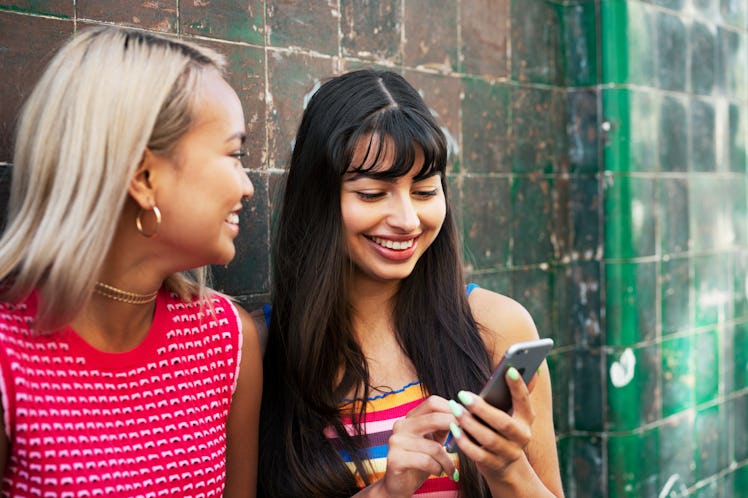 Friends laughing looking at April fools day quotes to use as captions for Instagram.