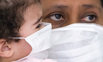 A woman holds in arms her daughter as they wait to be checked for Influenza A(H1N1) (swine flu) infe...