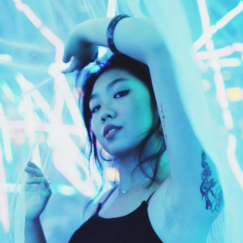 Young woman flushed in neon blue light, embracing the April 4, 2022 weekly horoscope for her zodiac ...