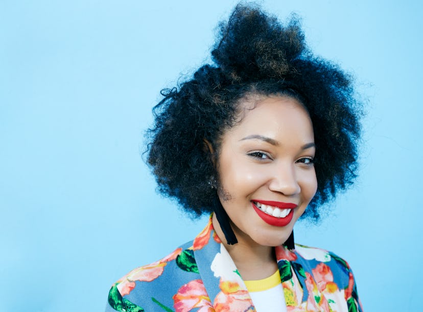 Young woman with curly hair smiling, knowing her zodiac sign will have the best week of April 4, 202...