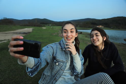 To friend girls sitting by the lake andand relaxing at sunset.