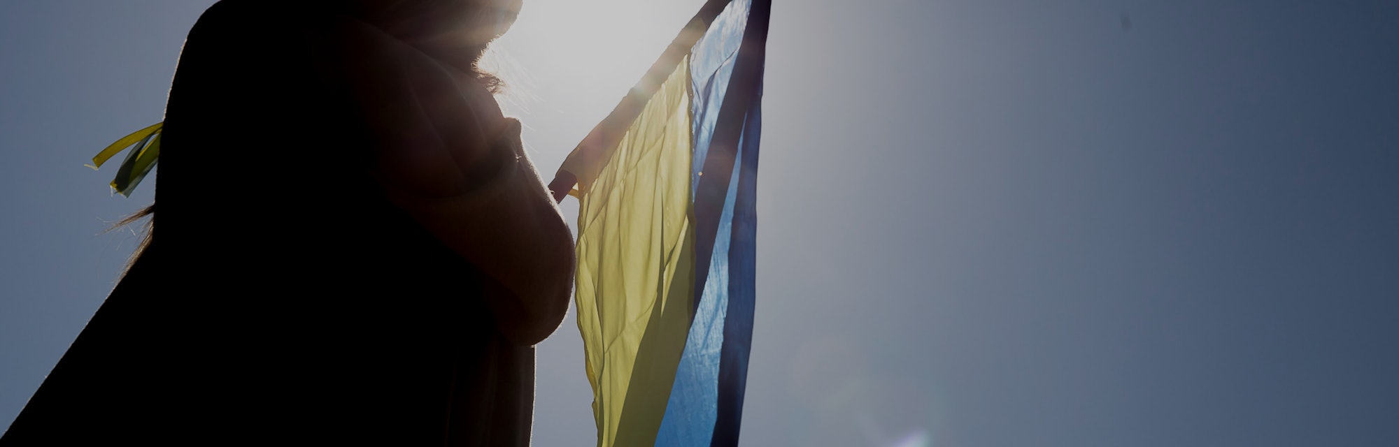 A girl waves the Ukrainian flag in the backlight in the support camp in her country, set up in Plaça...