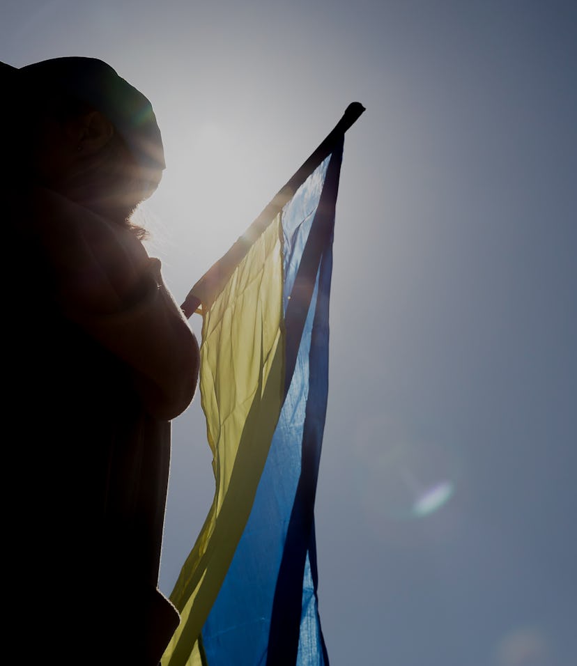 A girl waves the Ukrainian flag in the backlight in the support camp in her country, set up in Plaça...