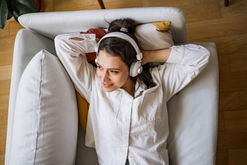 A woman lies on a couch listening to podcasts about women's history.