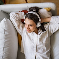 A woman lies on a couch listening to podcasts about women's history.