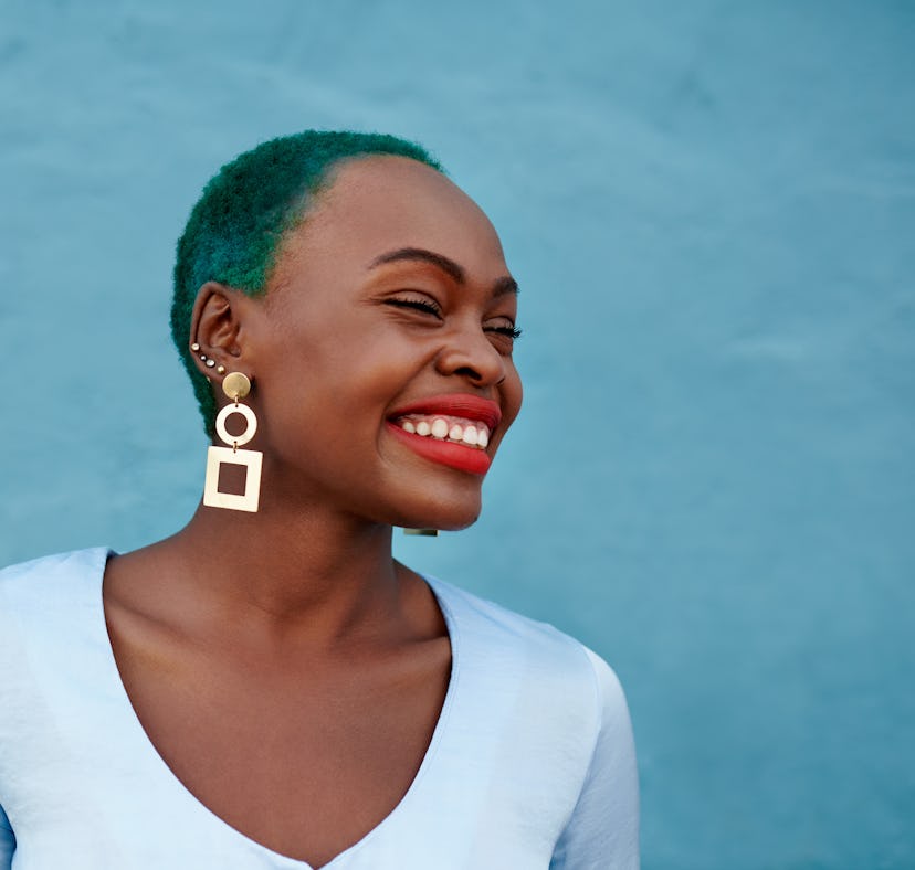 Young woman with green hair laughing and smiling during the week of of March 14, 2022, the best week...