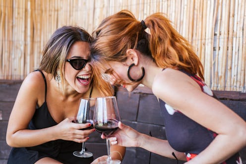 Two friends laugh over glasses of wine. Here's your daily horoscope for March 8 2022.