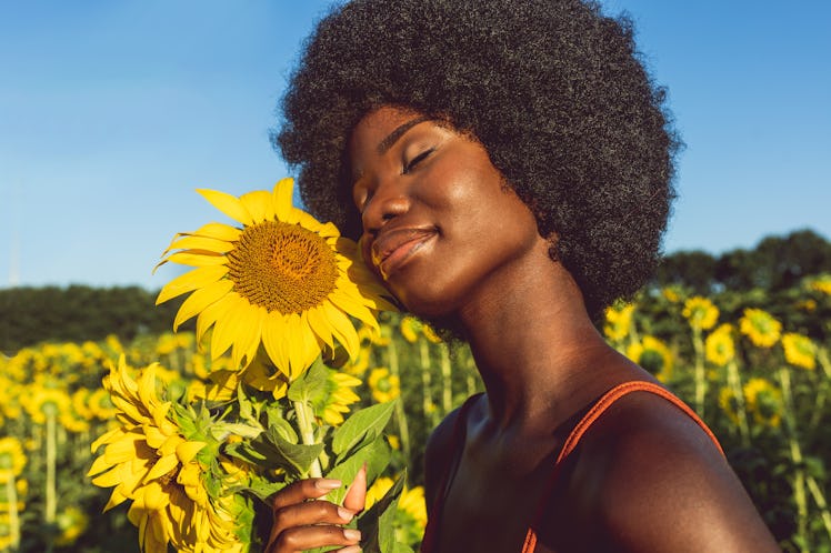 young woman golds sunflower to her face as she thinks about the 2022 spring equinox