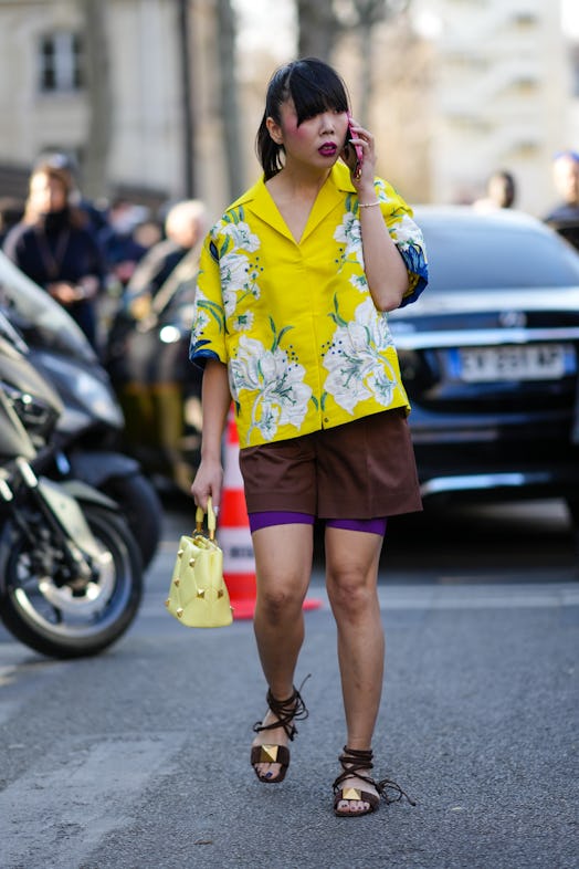 PARIS, FRANCE - MARCH 06: A guest wears silver earrings, a yellow with green and white print pattern...