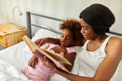 Mother and daughter in bed reading book together