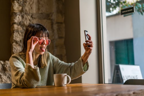 A woman takes a silly selfie to change her instagram profile picture.