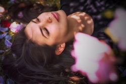 A woman lies in a field of spring flowers. Here's the spiritual meaning of the spring equinox.