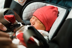 newborn getting strapped into car seat