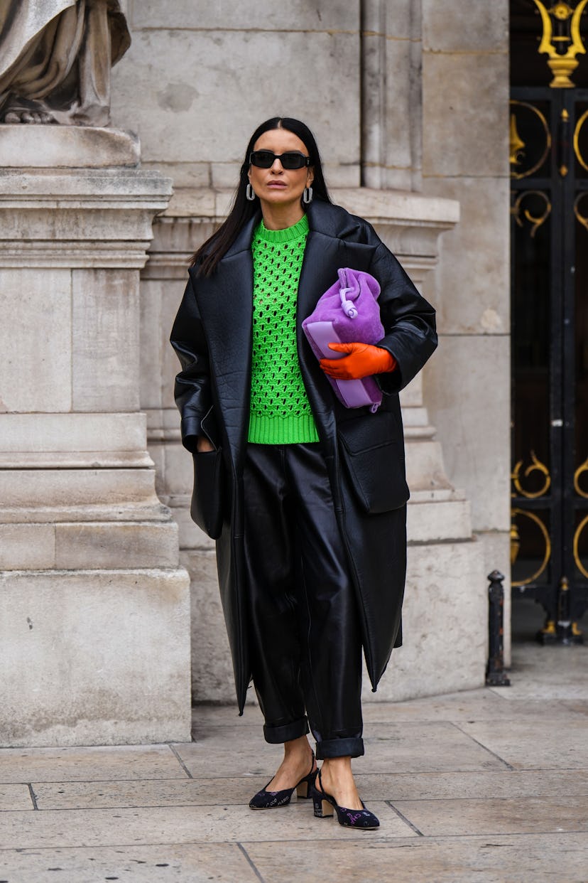 PARIS, FRANCE - MARCH 01: A guest wears black sunglasses, silver and rhinestones earrings, a green b...