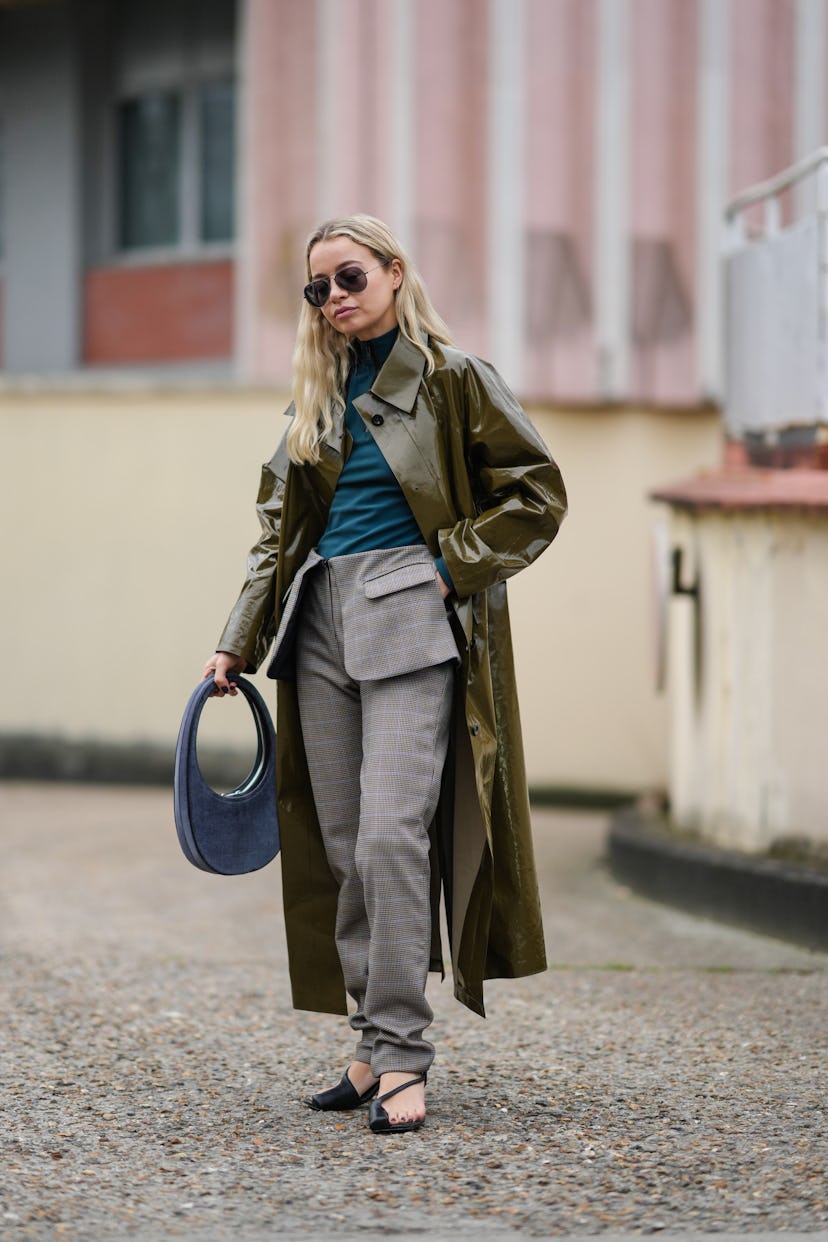 PARIS, FRANCE - MARCH 03: A guest wears black sunglasses, a blue pullover, a khaki shiny varnished l...