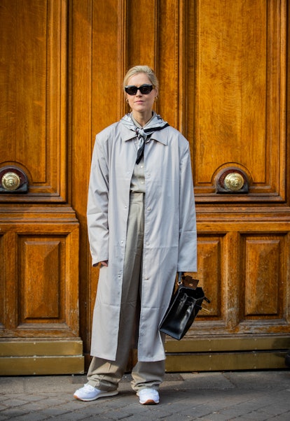 PARIS, FRANCE - MARCH 05: Linda Tol wearing grey trench coat, Tol sunglasses, scarf, beige high wais...