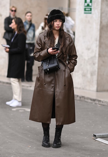 PARIS, FRANCE - MARCH 02: A guest is seen wearing a brown faux leather coat, black hat and black bag...