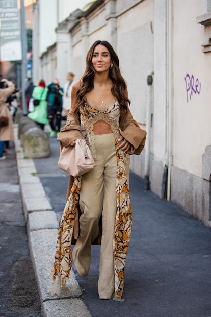 MILAN, ITALY - FEBRUARY 23: Tamara Kalinic seen wearing cropped dress with print, beige pants, coat ...