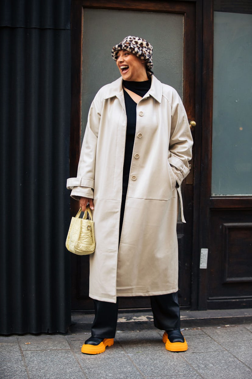 PARIS, FRANCE - MARCH 05: Model Maxie (Manuella) wears a fuzzy spotted bucket hat, tan trench coat, ...