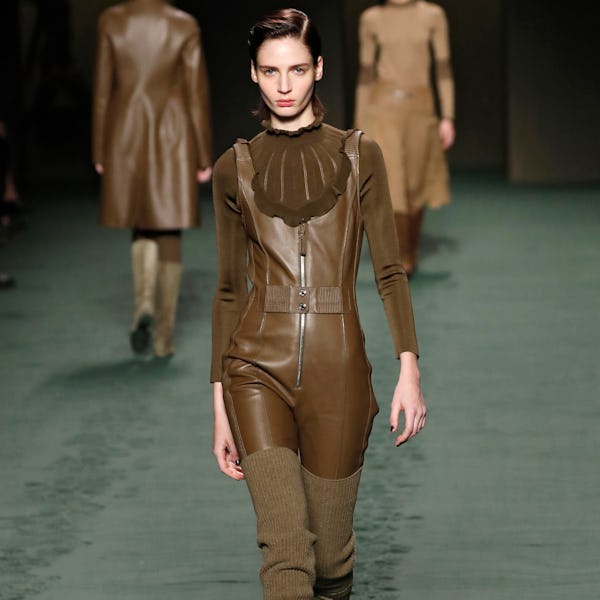 a model wearing a brown leather jumpsuit on the Hermès runway