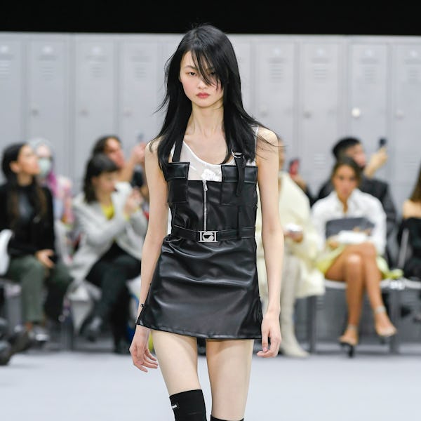 a model wearing a black leather mini dress on the Coperni runway