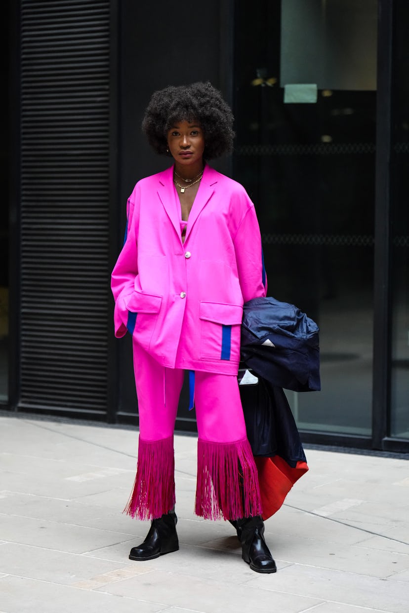 PARIS, FRANCE - MARCH 01: A guest wears gold chain pendant necklaces, a neon pink oversized shirt wi...