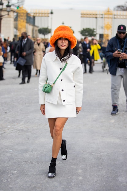 PARIS, FRANCE - MARCH 01: Yoyo Cao is seen wearing orange bucket hat, white blazer, skirt, green min...