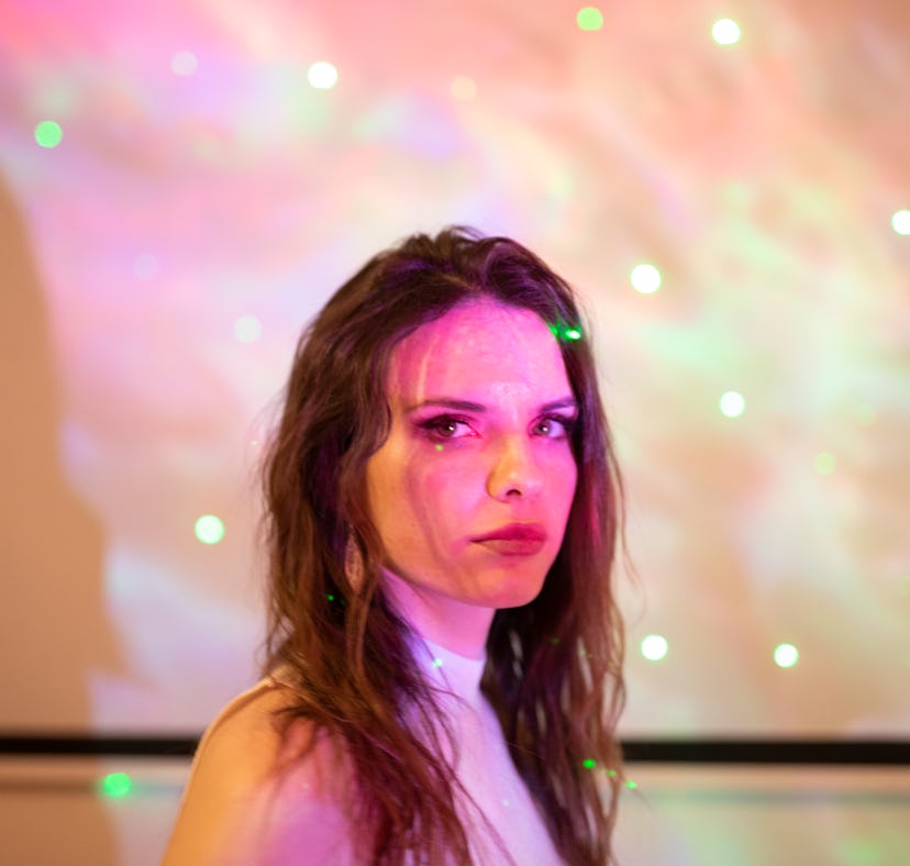 Young woman illuminated by starry lights, thinking about the March 2022 full Worm Moon on March 18, ...
