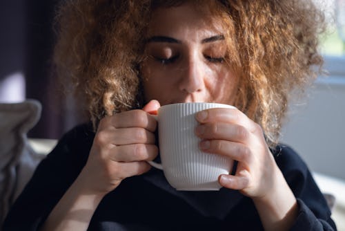 Young woman drinking a cup of coffee at home. Here's your daily horoscope for March 10, 2022.